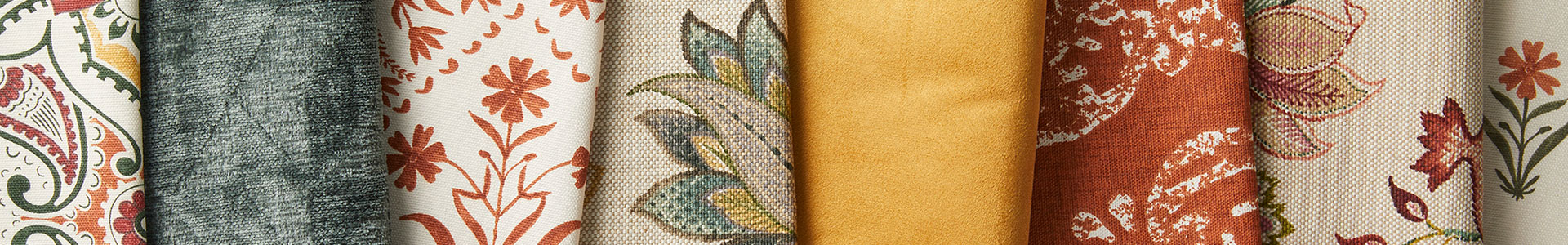 Stacks of home decor fabrics in fall colors and prints